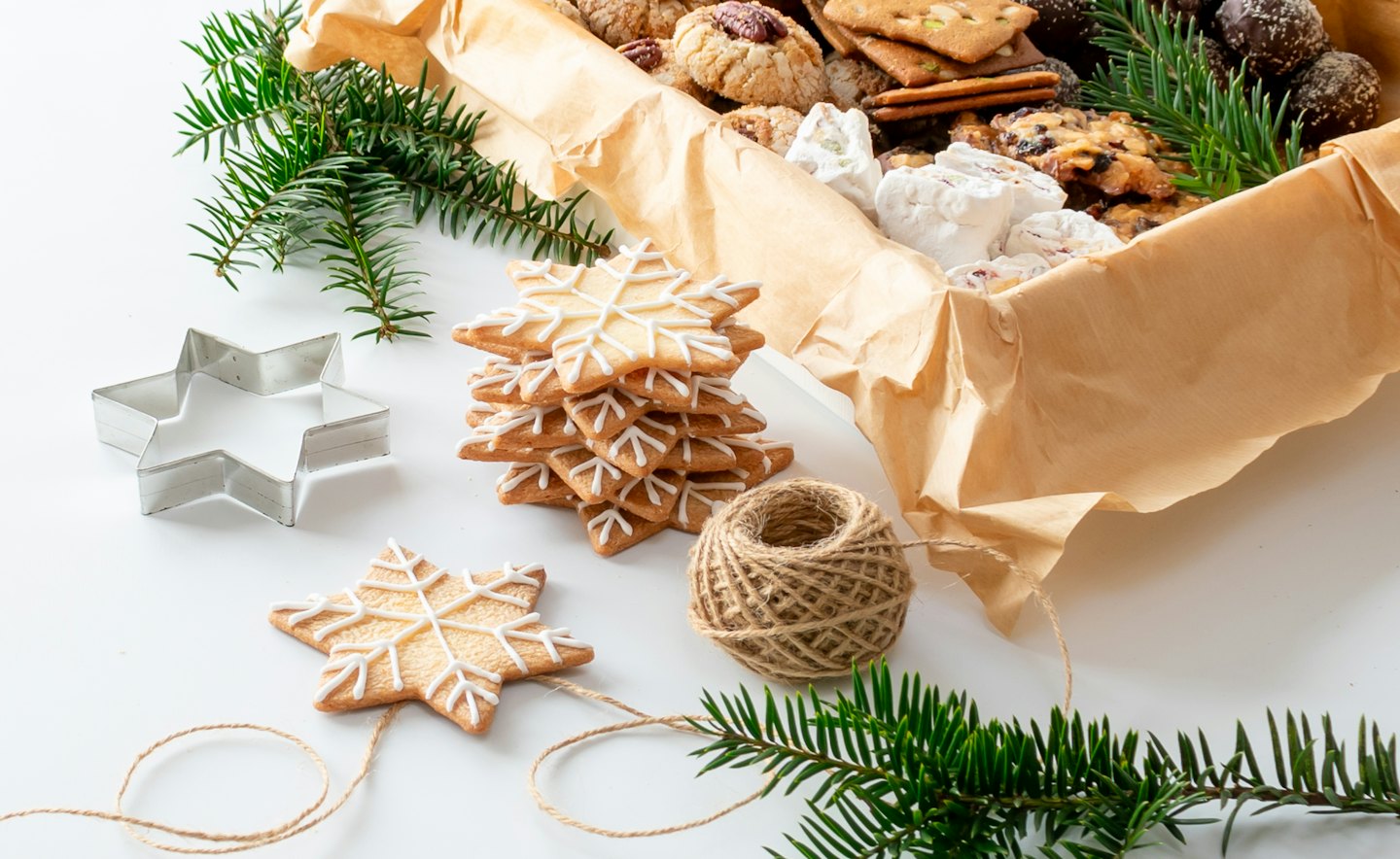 Homemade holiday cookies and gift supplies arranged on a table.
