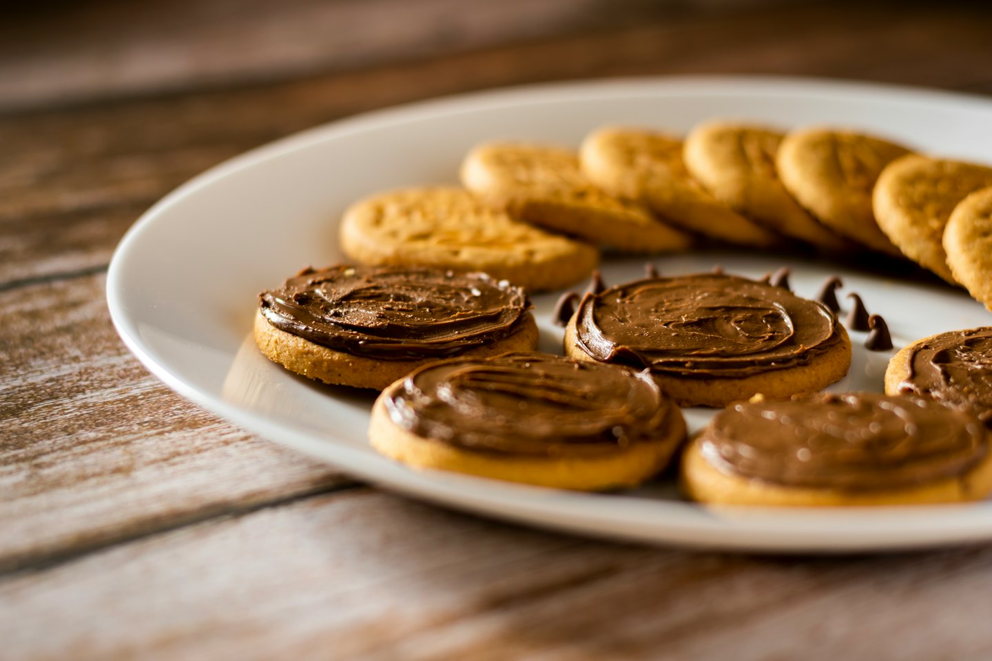 Assorted golden brown cookies sit on a white ceramic plate.